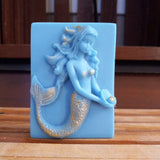 blue mermaid goats milk soap holding a pearl scented with plumeria and brushed with gold mica