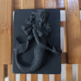 black mermaid holding a pearl activated charcoal and tea tree oil goats milk soap