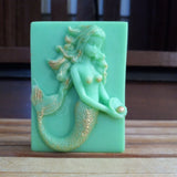 green mermaid holding a pearl goats milk soap scented with cucumber melon and brushed with gold mica