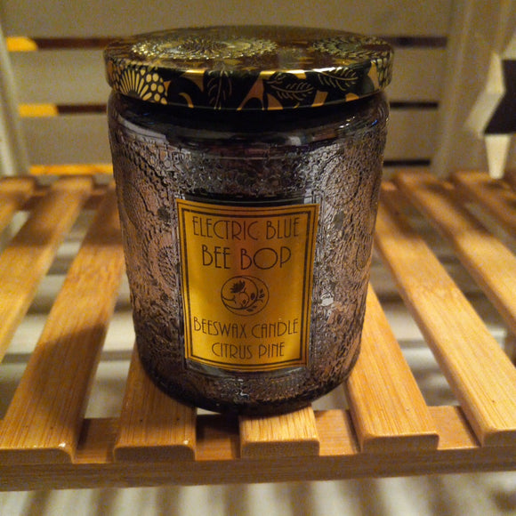 citrus pine scented beeswax candle in dark gray embossed glass with black and gold tin lid